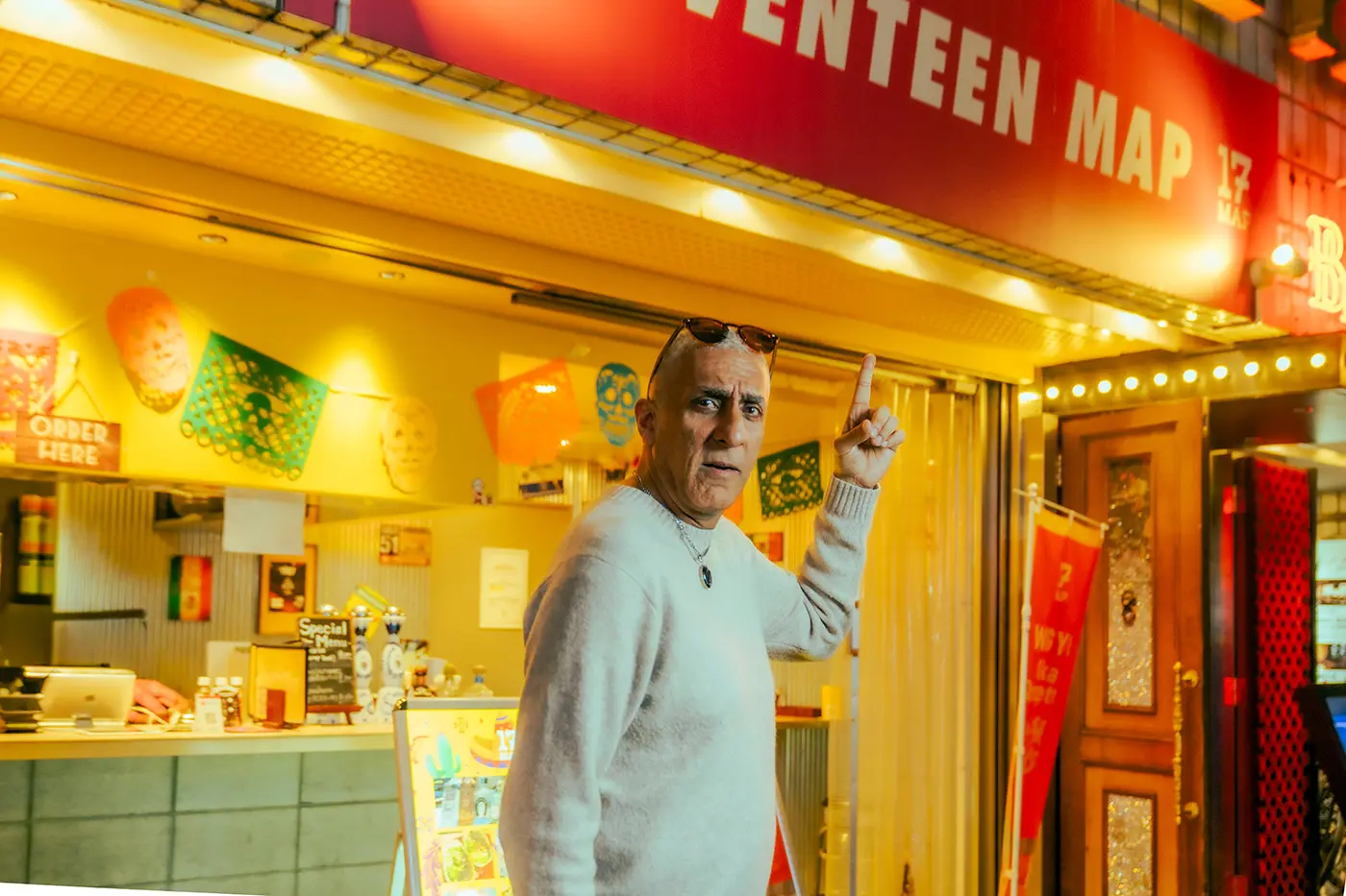 KISH 指著一家墨西哥餐廳，餐廳內部裝潢引人注目，色彩繽紛。