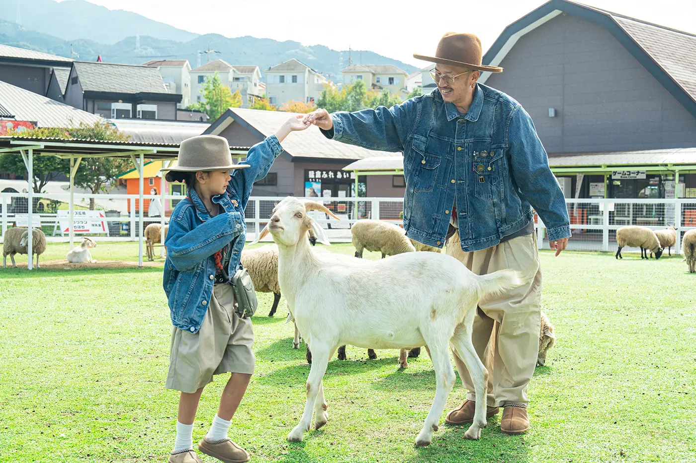 A parent and child interacting with goats