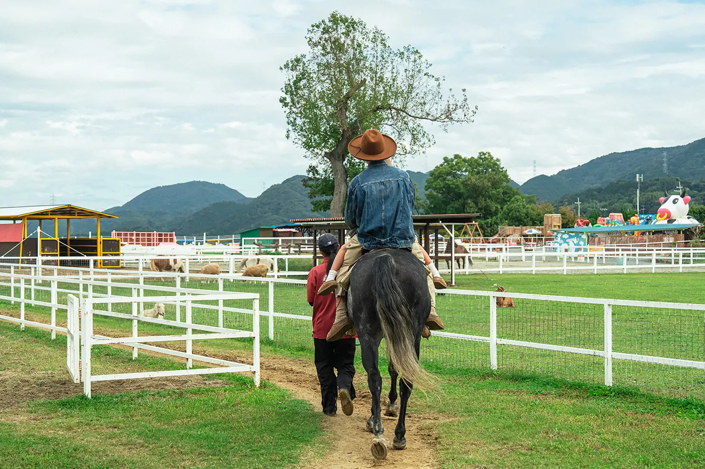 Rear view of parent and child experiencing horse riding