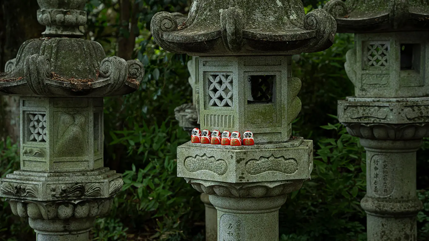 石灯篭の上にもダルマが並ぶ。