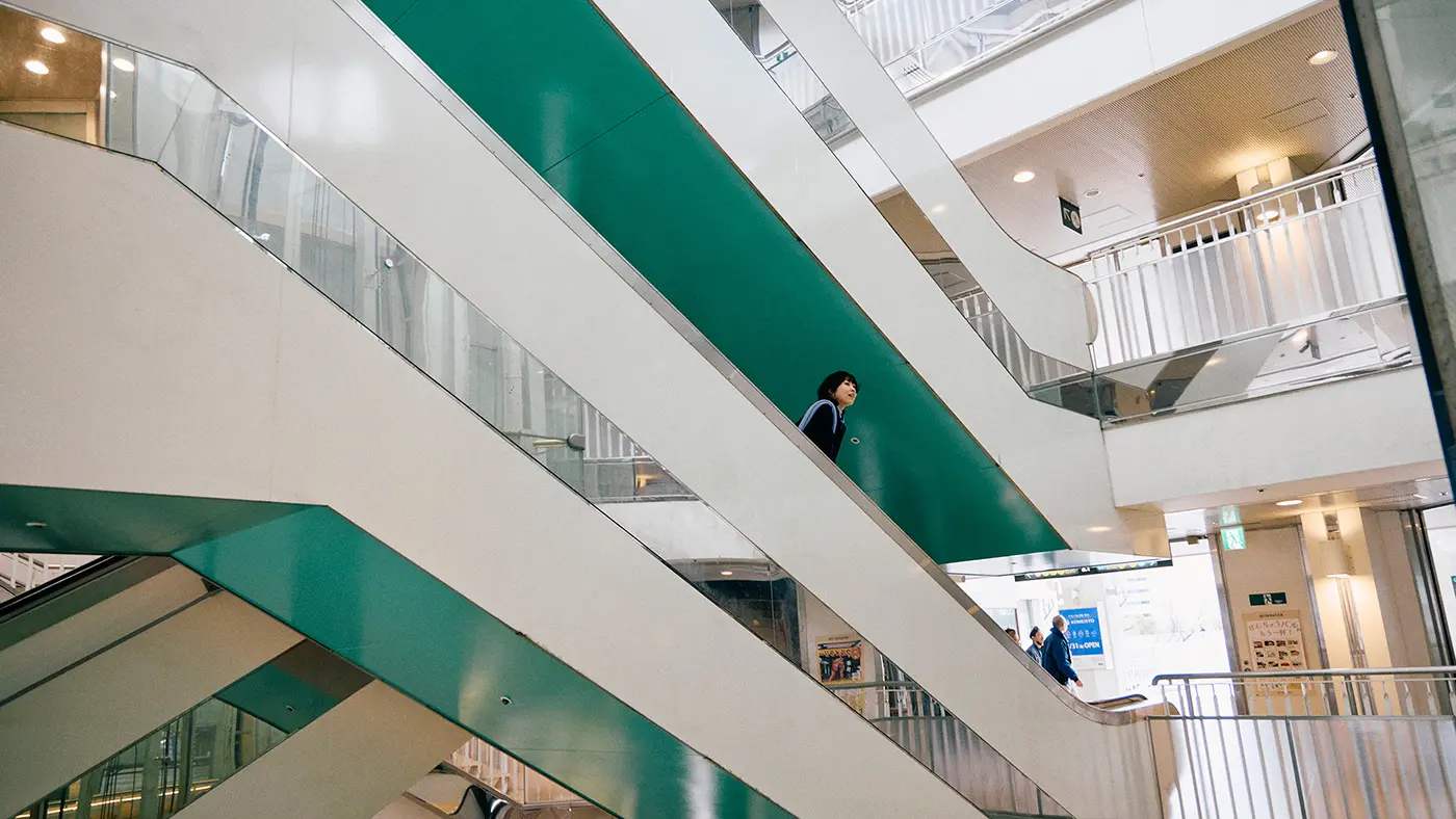 歩道橋を奥へ進むと、階段やエスカレーターが重なり合う吹き抜けが出現。