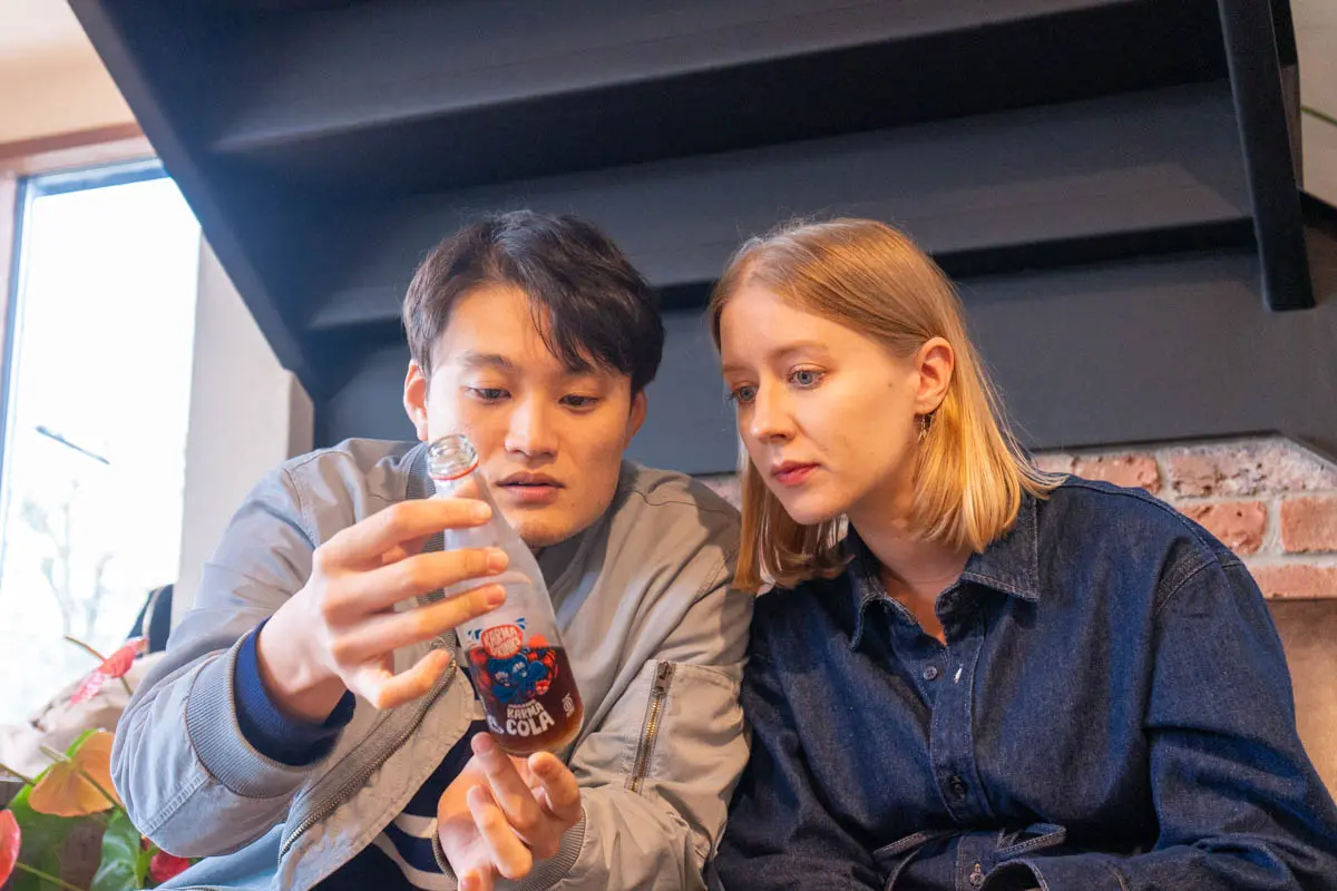 Anne and Yusuke looking at a bottle of Coke