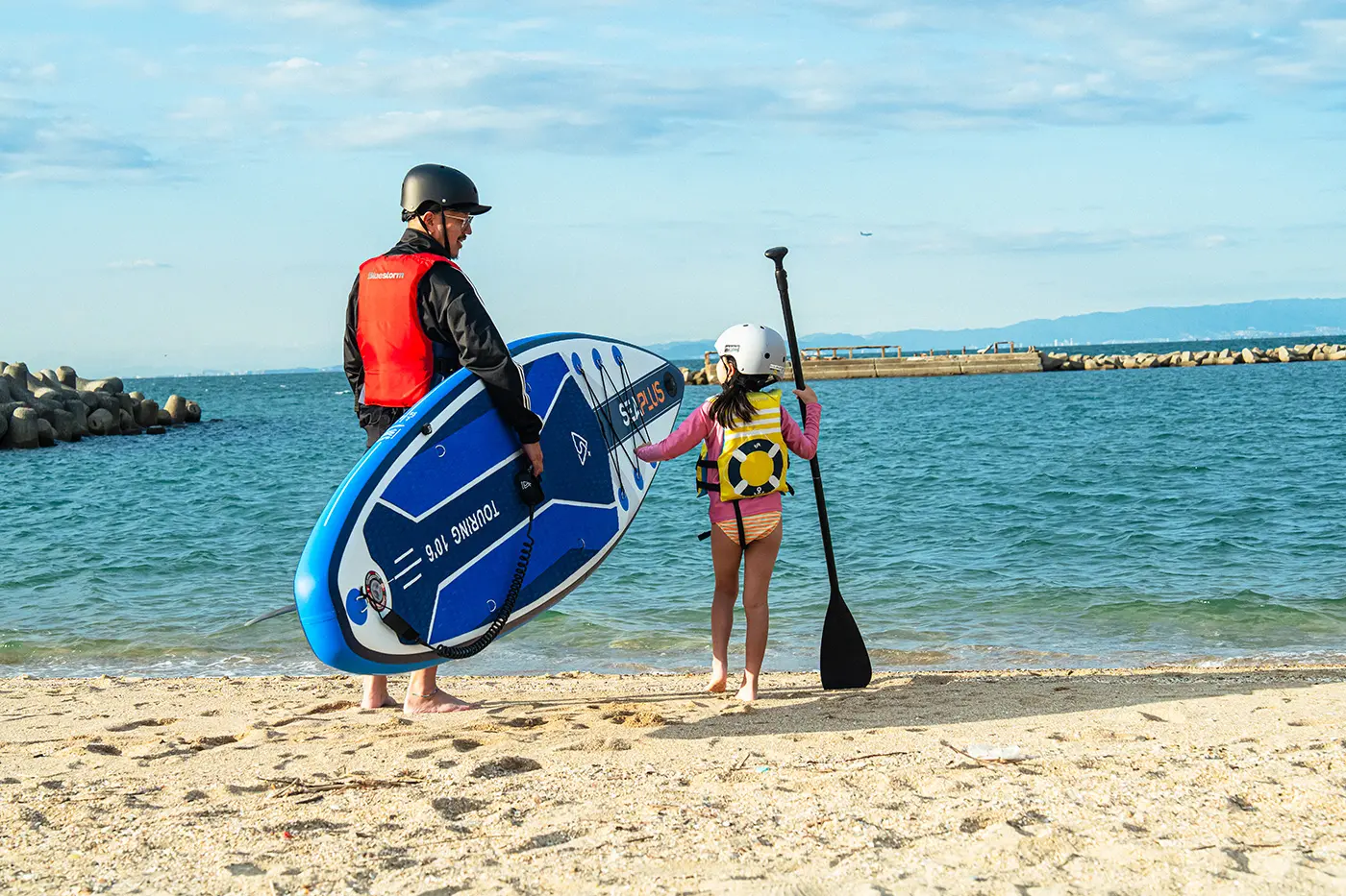 Parent and child enter the sea to do SUP
